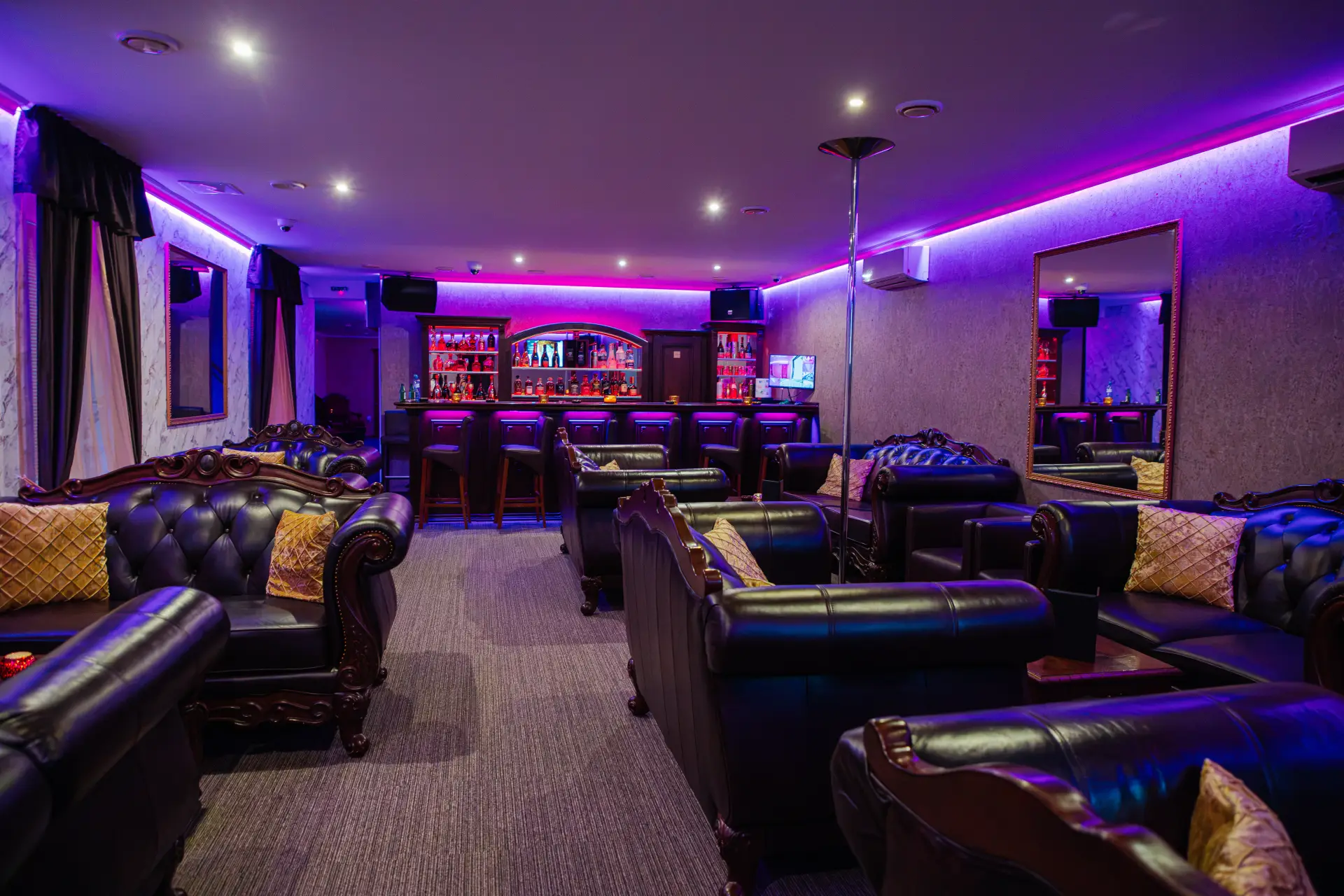 Lounge s koženými chesterfield sedačkami a barom v pozadí
