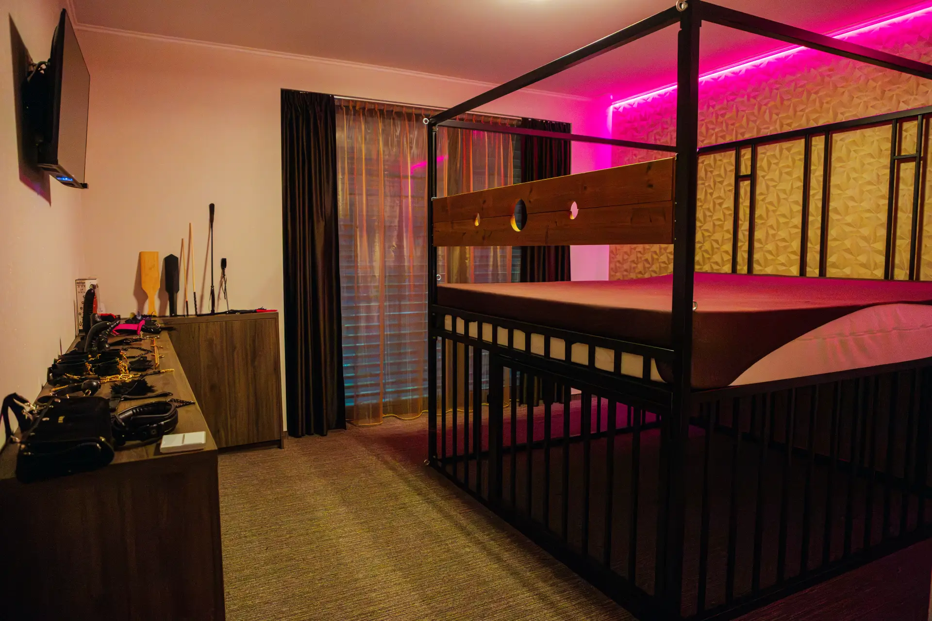 Themensalon mit schwarzer Metallkonstruktion, Holzbrett mit Öffnungen und rosa LED-Beleuchtung