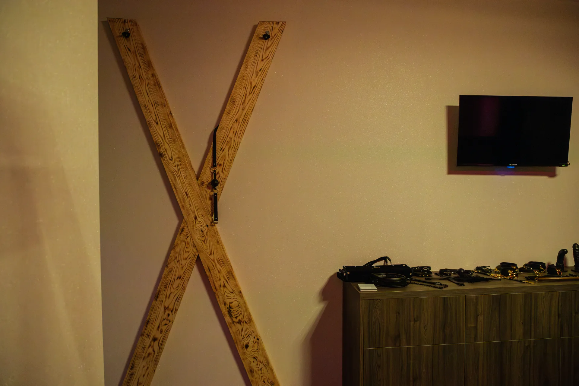 Hölzernes Andreaskreuz an der Wand des Themensalons neben einer Kommode mit Accessoires